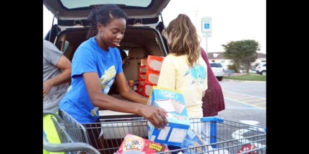 CCLP/LYNETTE SOWELL - DECA Club member Ariana Wilson helps load donated food items after a food drive held at Walmart on Friday. The club collected food for the CCHS weekend food backpack program to help fellow CCHS students in need.