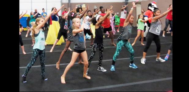 CCLP/BRITTANY FHOLER - Kids and mascots learn the choreography to the official dance at the National Dance Day held at GymKix Saturday afternoon.
