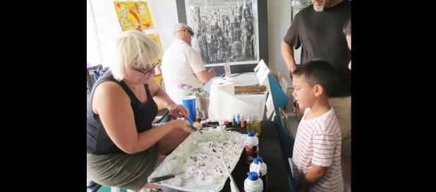 Julie Landrum demonstrates how to create marble designs on paper using shaving cream and food coloring at the Sip and strut event held in Downtown Lampasas Thursday evening.
