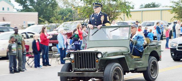 CCLP/LYNETTE SOWELL - World War II veteran and Pearl Harbor survivor Ret. 1SGT Henri “Hank” Grenier stands in a military jeep as he makes his way through the parade route, Friday.