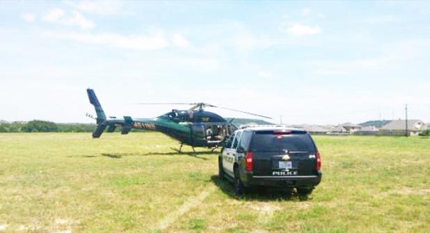 COURTESY PHOTO - A helicopter pilot was using the open green space at House Creek Elementary School to land in a non-emergency situation. In this photo, a Copperas Cove police department officer parked a department SUV beside the helicopter to speak to the pilot.