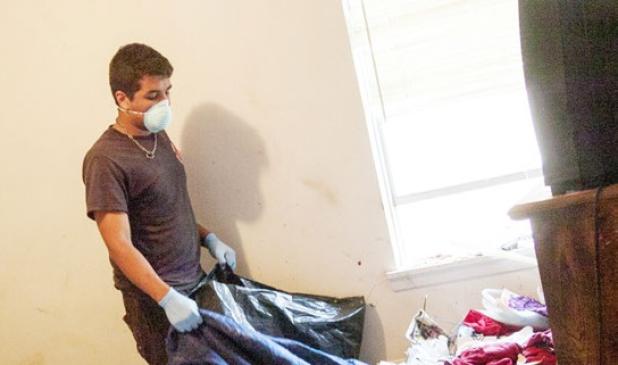 Antonio Lopez works to remove trash from the master bedroom of the home. Garbage was piled from the floor nearly touching the ceiling in parts of the home.