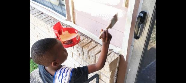 COURTESY PHOTO - Little Mister Rabbit Fest Azaire Barrett, 6, gets busy painting near the front door of My Brother’s House, the food pantry of the Holy Family Catholic Church, on Saturday. It took 15 volunteers more than 10 hours to paint the facility.