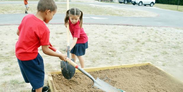 CCLP/LYNETTE SOWELL - Cove Charter Academy first grade students Nicholas Jeffries and Carmen Barragen add more dirt to planter beds at the campus’ garden area. The students are growing an organic garden and learning about rainwater harvesting.