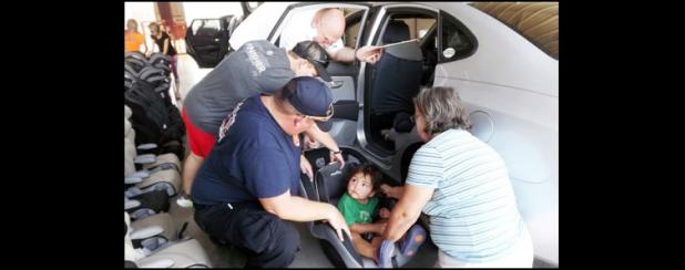 CCLP/PAMELA GRANT -  Firefighter Kris Hurst shows Shirley Anderson how to properly strap her grandson, AJ Zavala, into his new car seat.