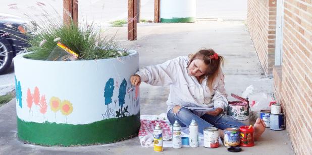 CCLP/LYNETTE SOWELL - Joan Kelley paints Texas wildflowers on one of six concrete planters in downtown Copperas Cove on Friday. Kelley, an area artist, volunteered her time and skills to help complete the project with the Keep Copperas Cove Beautiful Commission.