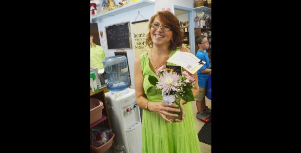 CCLP/FILE PHOTO - Michele McGuire, owner of Michele’s Floral and Gifts holds a flower arrangement given out on Lonely Bouquet Day. McGuire is seeking a buyer for her shop.