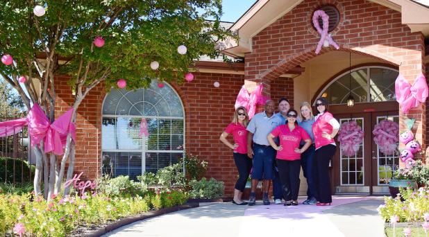 CCLP/LYNETTE SOWELL -- The staff at Clear Creek Meadows Apartments stand in front of their decorated entryway. The business was awarded first place in the Pink Out The Town contest held by Pink Warrior Angels.