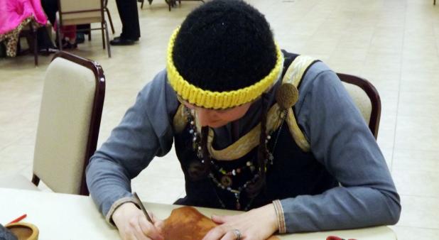 CCLP/PAMELA GRANT - Wendy Marsh works on tooling leather at the medieval workshop hosted by the SCA at the Copperas Cove Public Library. Here she works on finishing off her greaves which will be worn when she participates in rapier fighting.