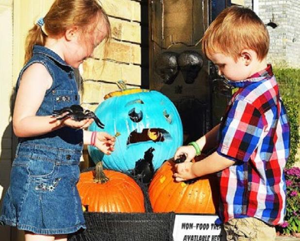 Colin and Isabella Maybury look at their family’s Halloween display with teal pumpkins, noting non-food treats available for children with food allergies.