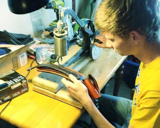 Cove FFA Chapter President Daniel West puts the final touches on his carved leather gun belt to enter in the home economics contest at the Coryell County Youth Fair which run Jan. 15-17.
