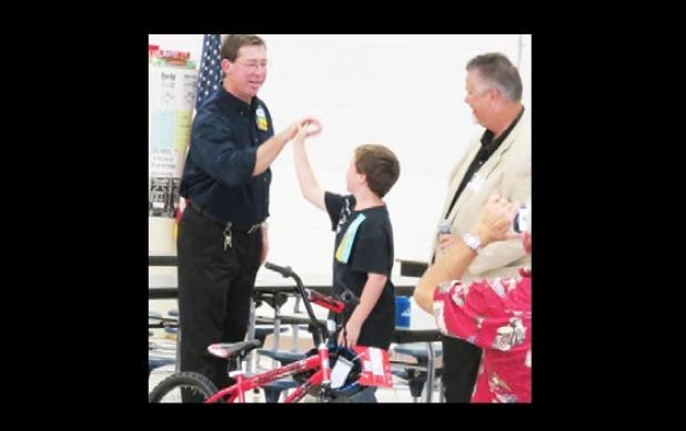 Joshua Garretson celebrates winning a new bike with high fives for members of the Rotary club and Wal-Mart.