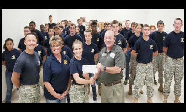 Battalion Commander Jessica Temples accepts checks from Mark Peterson representing the Morning Exchange Club and the Chamber of Commerce Military Affairs Committee and Marty Smith on behalf of her husband’s Jerry Smith Scholarship fund.