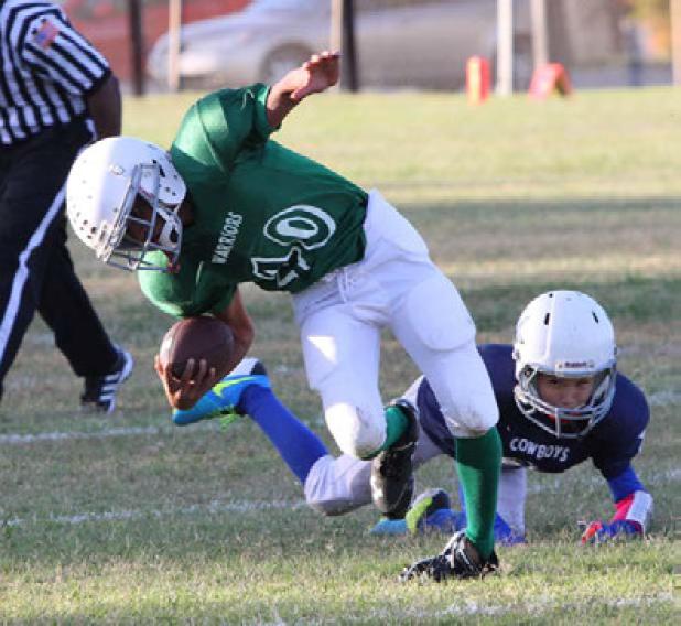 Warriors’ running back Asher Fugitt is tripped from behind by Cowboys’ Bobby Joe Millican during their playoff game Saturday at the Avenue E Sports Complex. The Warriors advanced to Saturday’s semi-finals against the Horned Frogs.