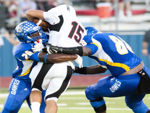 Copperas Cove senior defenders Michael Sumrall (26) and Tyrell Thompson wrap up Lake Travis junior running back Abe Willows during the first half Friday at Bulldawg Stadium.