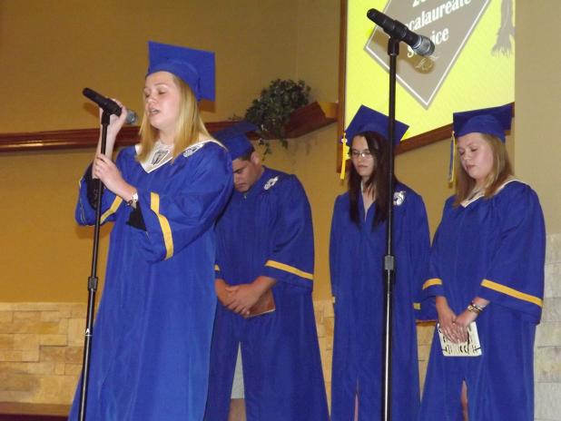 2015 graduate, Hannah Legare, offers a prayer to the 2015 graduating class at the 2015 CCHS Baccalaureate Service. Fellow graduates, Coleton Tuiasosopo, Stormi Hall, and Joanna Legare, stand behind her.

