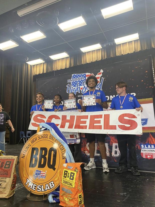 Courtesy Photo  The Copperas Cove High School Bulldawg BBQ team receive their 3rd place award on the podium at the recent National High School Association’s Regional BBQ Competition in Elgin. Bulldawg BBQ advances to compete at the Texas State High School BBQ Championship will take place on May 2, 2026. 