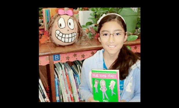 Haylie Anicama shows off her pumpkin created to look like her favorite book character from Dear Dumb Diary as part of Martin Walker Elementary School’s Storybook Pumpkin Patch project.