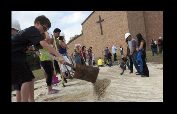 Members of the Holy Family Catholic Church turn dirt during a ceremony marking the expansion of their campus