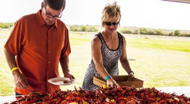 Guests pile crawfish, sausage, corn and potatoes into their boxes at the 7th annual crawfish boil at Texas Lagato winery in Lampasas.