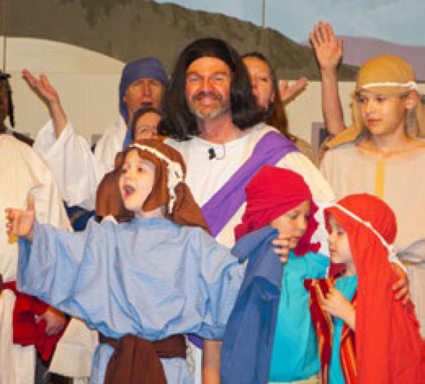 Sid Sharp, center, is surrounded by children as they run through a dress rehearsal of the annual play.