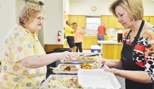 Margaret Martin, left, helps Lulu Maples prepare a boxed catfish and brisket meal at Pidcoke United Methodist Church’s Big Feed on Saturday.