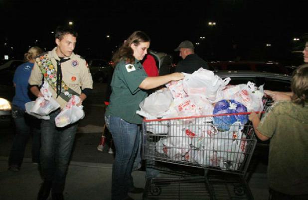 Scouts from Troop 224 help move bags of donated food for transport during the 25th annual Food For Families food drive Friday evening.
