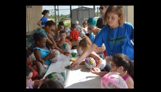 Camp Discovery counselor Hailey Hensley gives the Roadrunner campers a hand with their paper mache balloons.