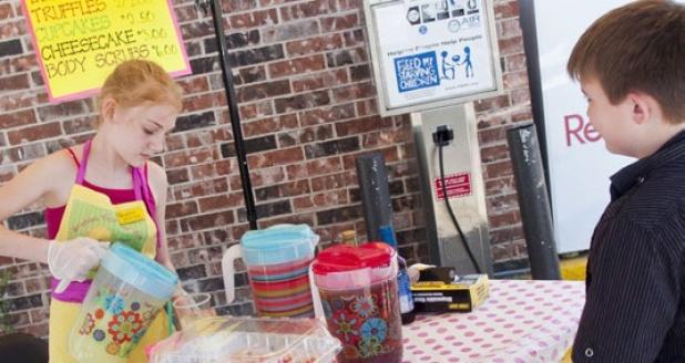 Jordan Kinne pours a glass of lemonade for Korey Keller outside the 7-11 as she operates her own stand for the second consecutive year.
