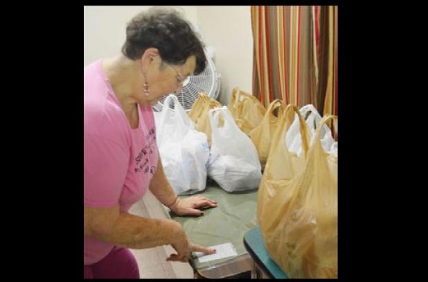 Nancy Cranfill checks the menu for the food bags at Free Lunch Saturday held at Five Hills Assembly of God.