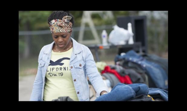 Esha Cole, browses through piles of clothes as she visits the Bountiful New Life Church of God in Christ’s final garage sale in the parking lot off Ave. E, Saturday.