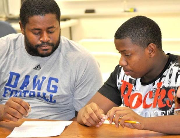 CCHS Coach Cecil Johnson tutors Bulldawg football player Darish Robinson in World Geography through the P.A.S.S. Club where more than 200 athletes come for assistance with their studies to boost their GPAs and keep them playing in the school’s sports programs.