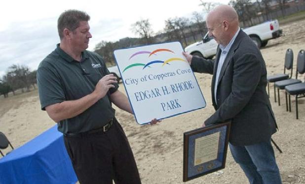 Parks and Recreation director Joseph Pace presents Brett Rhode with a copy of the sign of the park that bears his fathers name. Edgar H. Rhode Park is open for play and currently has an open field for soccer.