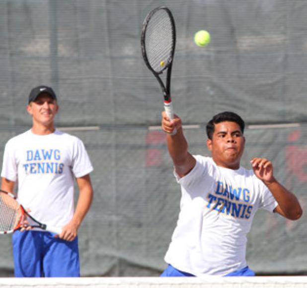 Cove’s Jake Abraham hits an overhand volley as doubles teammate Nic Fletcher looks on during their District 12-6A tilt at Harker Heights on Tuesday.