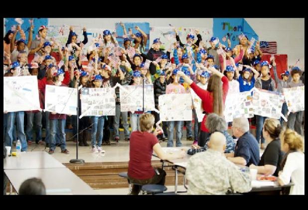 Students perform a patriot barrage of songs during a celebration honoring veterans, Monday morning. Ralf, a veteran service dog, led the parade of veterans through the halls of the campus.