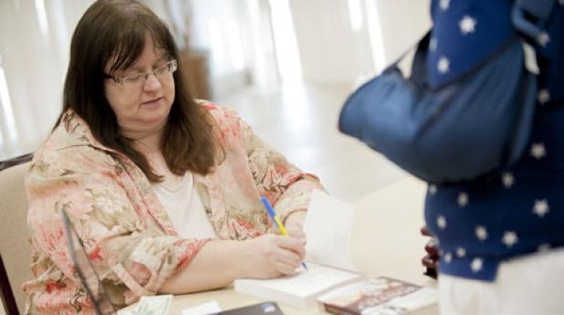 Lynette Sowell adds a personalized message to a book as she greets her readers during the book launch party for A Season of Change, her twentieth published novel. A season of Change is the first in a three part series.