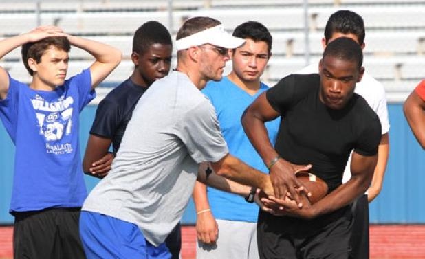 Copperas Cove assistant coach Ryan Youngblood hands off the  all to incoming freshman Miles Alexander as others look on during running back drills on Monday as part of the 2014 Copperas Cove NFL Football Camp at Bulldawg Stadium.