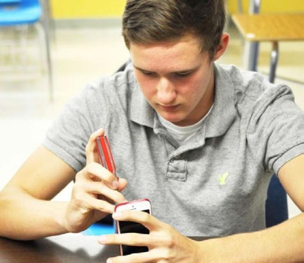Cody Amaro works on a student’s iPhone at Copperas Cove High School on Thursday. Cody started the company with Dylan his brother in 2011.