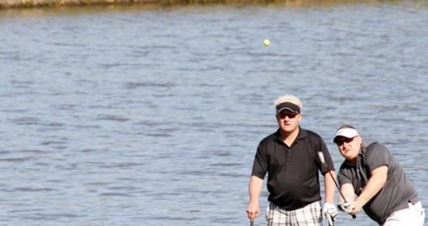 Joe Garland watches his pitch shot travel towards the pin on hole eight as his teammate Fred Cosper looks on during the Copperas Cove Lions Club 26th Annual Golf Tournament Saturday at the Hills of Cove Golf Course in Copperas Cove.