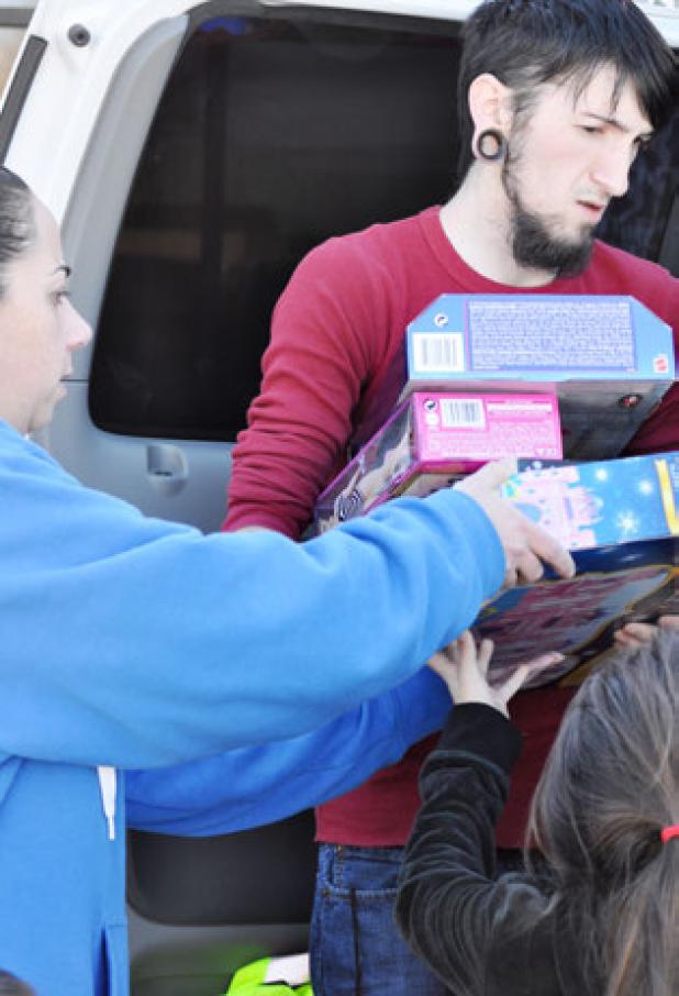 Natalie Amir hands toys to Outcry Tattoos Artist Isaic Billian to deliver to Communities in Schools in Copperas Cove in time for Christmas. Billian and fellow employees donated half of their earnings during the month of December to purchase the toys for homeless children in Cove.
