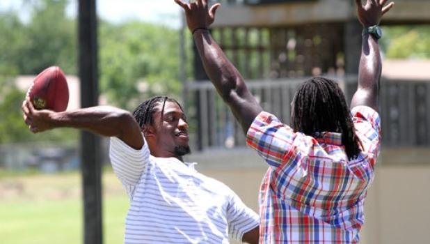 Heisman trophy winner and Washington Redskins quarterback Robert Griffin III, throws a pass as Charles “Peanut” Tillman defends during the filming of a commercial for USAA (United Services Automobile Association) on Wednesday at Copperas Cove High School.