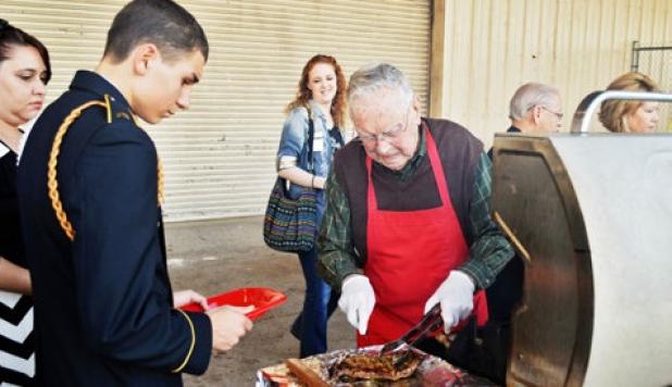Woody Shemwell, one of seven grill volunteers, checks a steak at Thursday night’s military affairs banquet hosted by the chamber of commerce.