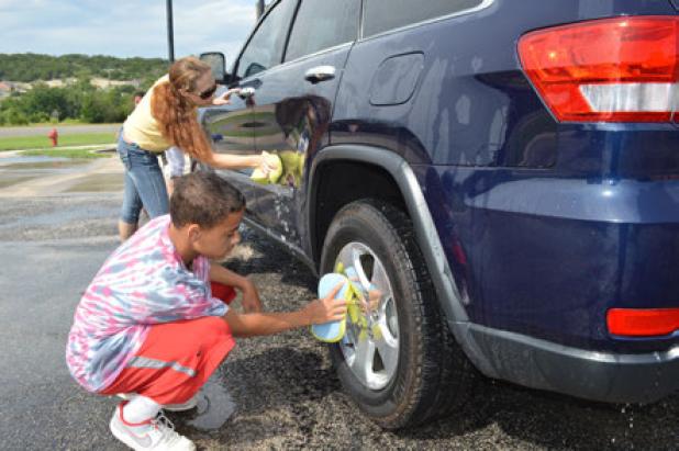Stephanie Burkholder and Shannon Bryant wash a car at Saturday’s fundraiser for The Rainbow Room.