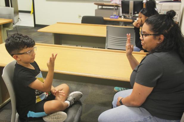 Leonardo Torres and his mother share a moment of connection while practicing sign language together, one of the many family-bonding moments from the CTC class.