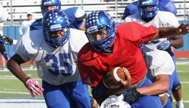 Copperas Cove junior quarterback Manny Harris is tackled from behind by linebacker D’Mani Bunn-Peapealalo during a Blue-Gold scrimmage Thursday at Bulldawg Stadium.