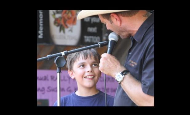 Tackle football player, Arin Stack, 10, takes an opportunity to thank people for their donations to help save tackle football as Dave McBride, owner of Dave’s Sports Bar and Grill, holds an auction during a benefit to raise funds for the program.
