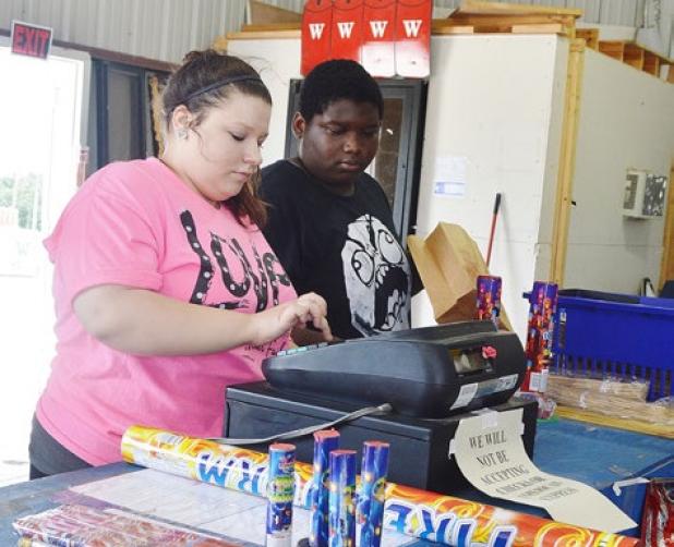 Megan Hunt totals a customer’s purchases while John Williams bags them at Mr. W’s Fireworks west of Copperas Cove.