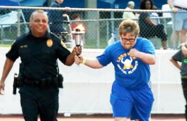 Copperas Cove Police Department Public Information Officer Martin Ruiz carries the torch with Alex during the opening ceremonies in Arlington.
