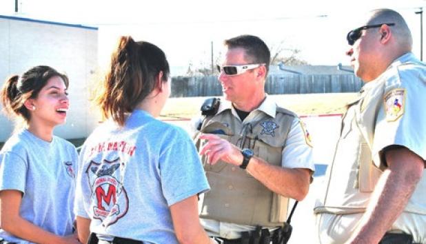 Manor High School juniors Katley Ramirez and Reyna Villalovos speak to Coryell County Sheriffs Rob Atkins and Eddie Rodriguez after their felony traffic stop competition Saturday at Copperas Cove High School.