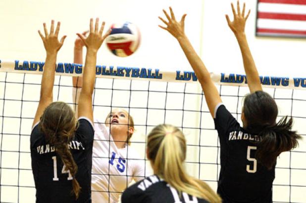 Copperas Cove senior Savannah Cook hits into the Vandegrift defense as Jacqueline Ribeiro (14) and Bella Benoit defend during their game Tuesday at Bulldawg Gymnasium. Cove won 21-25, 25-12, 25-16, 25-22 to move to 2-0 on the season.